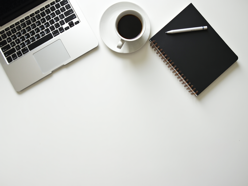 Ein ruhiger Arbeitsplatz mit Laptop, Kaffeetasse und Notizbuch, der Einfachheit und Fokus betont.