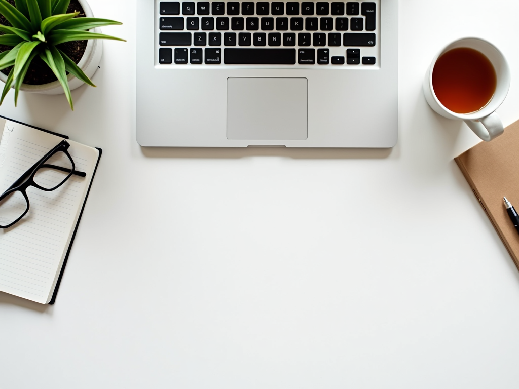 Ein minimalistischer Schreibtisch mit Laptop, Notizbuch und Tee
